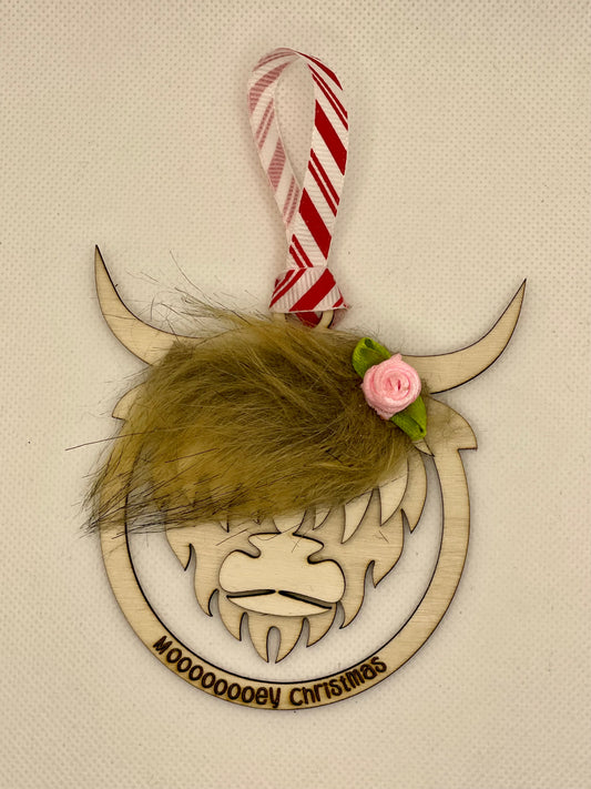 Highland cow tree decoration with text "Mooey Christmas". Item has fluffy hair to look like a coo's fringe. Comes with a pink rose on, and finished with hanging ribbon.